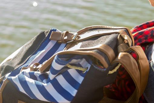 Backpack of traveler on wooden pier on lake.