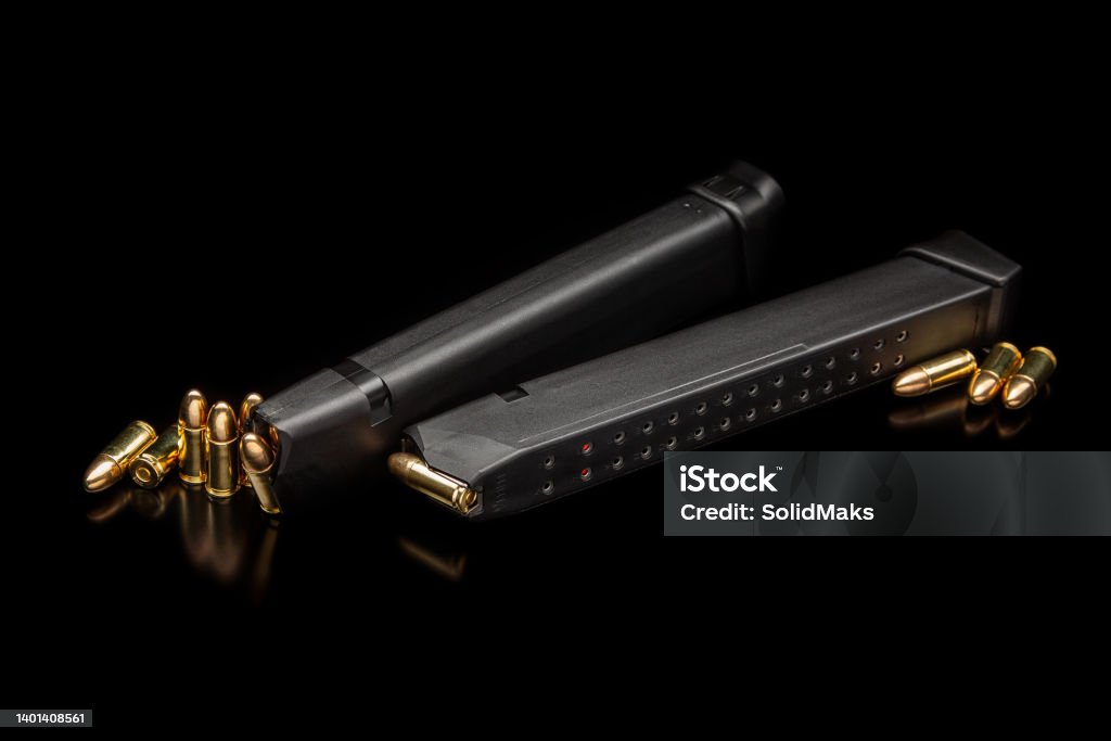 Pistol cartridges 9 mm on a smooth glossy surface with reflections. Ammunition for pistols and PCC carbines on a dark background. Ammunition Magazine Stock Photo