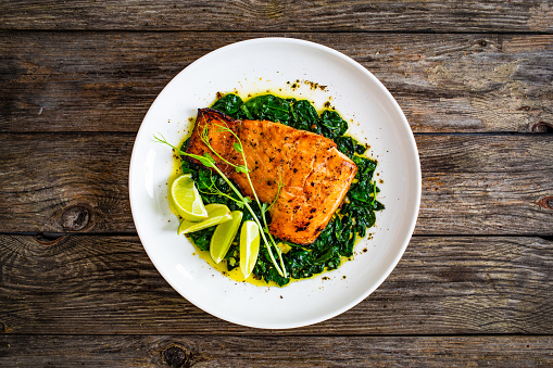 Fried salmon steak with capers and lime on wooden table