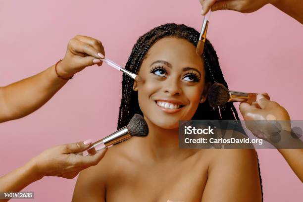 Happy Smiling Young Adult Woman With Dreadlocks Looking Away At Copy Space On A Pink Background With Hands Holding Makeup Brush Cosmetics Around Face Stock Photo - Download Image Now