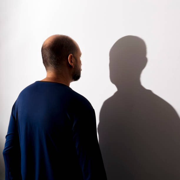 istock Portrait of a man and his shadow against white wall background. 1401413321