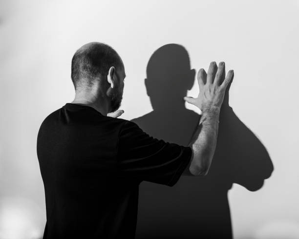 istock Portrait of a man and his shadow against white wall background. 1401413332