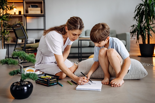 Mother and son sit on the floor and draw