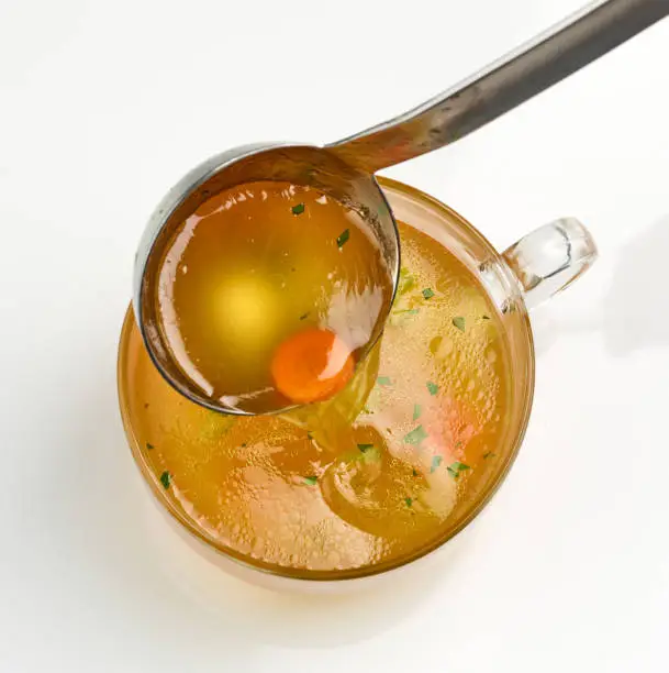 cup of fresh chicken bouillon on white background, top view