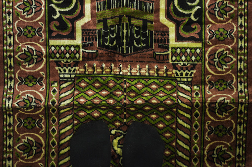 closeup woman feet wearing a black socks and praying for Allah in the mosque