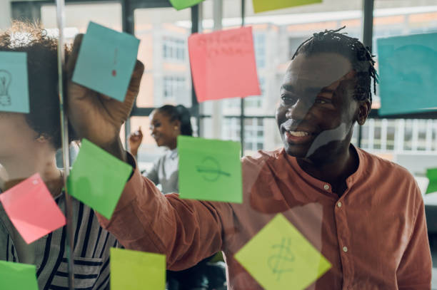 istock Multiracial team at work writing ideas on sticky notes on the glass wall 1401420256