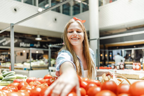 Young woman chooses and buys fresh vegetables at the market stock photo