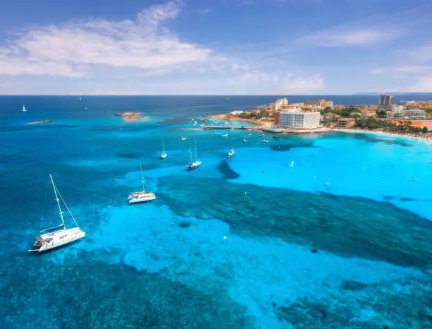 Photo of Aerial view of boats and luxury yachts in the clear sea at sunset in summer in Mallorca, Spain. Colorful seascape with lagoon, azure water, sandy beach, city. Balearic islands. Top view. Travel