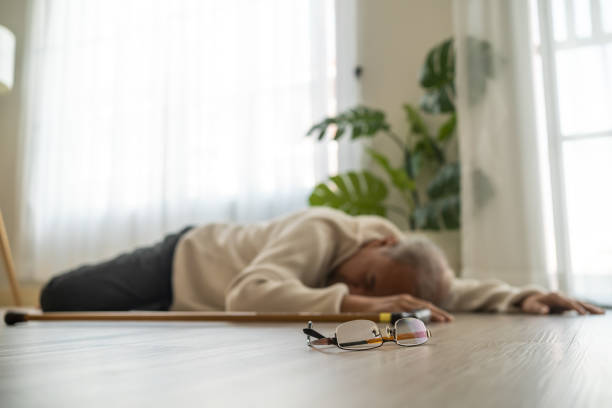 Asian senior male falling on the ground while walk with walker at home. Elderly older mature grandfather having an accident after doing physical therapy alone after retirement in living room in house. stock photo