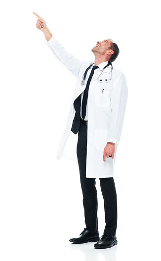 Side view of aged 40-44 years old with short hair caucasian young male doctor standing in front of white background wearing lab coat who is laughing who is pointing