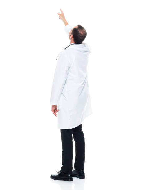 giovane medico caucasico in piedi di fronte a uno sfondo bianco indossando un camice da laboratorio - moving up looking men people foto e immagini stock