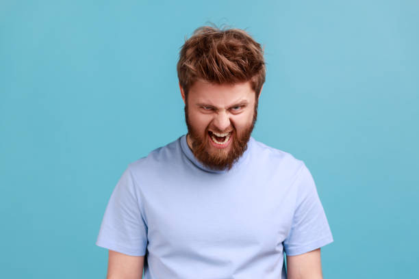 istock Man in blue T-shirt standing and screaming with anger, expressing aggression, swearing with someone. 1401432698