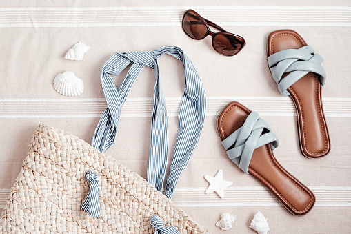 Summer vacations flat lay with beach accessories. Slippers, sunscreen, seashells over beach towel background Travel, tourism concept. Top view