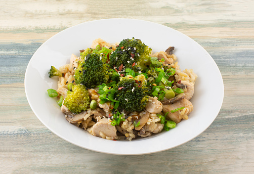 A top view of a tasty dish with a roasted chicken breast, brown rice, broccoli, and cauliflower