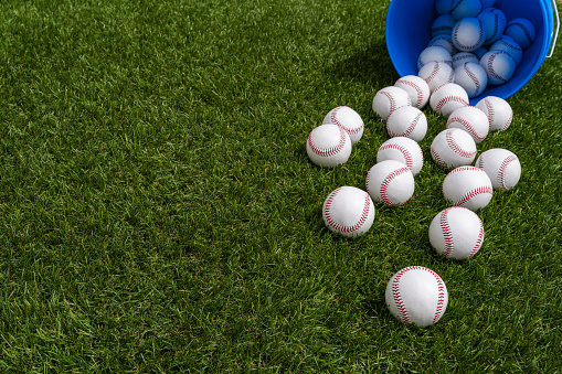 Middle Aged Redhead Father working hard during a baseball coaching session for his daughter at a training pitch on a sunny day