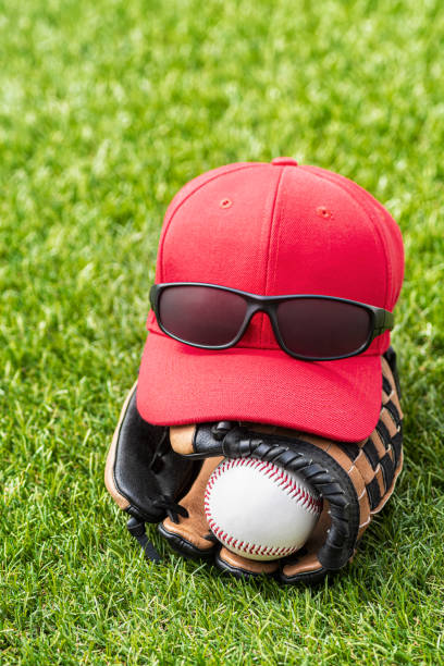 nowy baseball w rękawicy na murawie, z czapką z daszkiem i okularami przeciwsłonecznymi siedzącymi na górze - baseball cap cap green red zdjęcia i obrazy z banku zdjęć