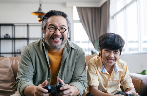 Son and dad playing video game at home