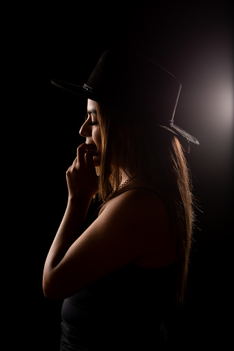 portrait of young woman with hat on black background.