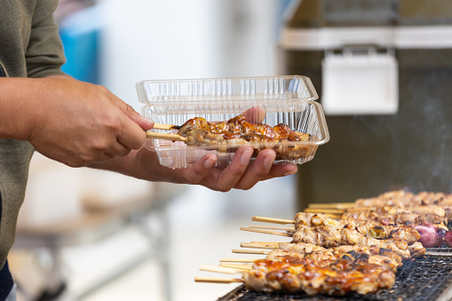 Skewers with chicken being grilled and ready to serve at a Japanese street market.