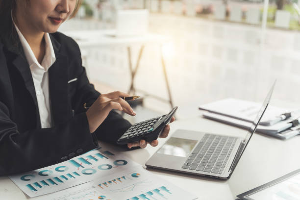 istock Businesswoman using calculator and laptop computer for analysis maketing plan, Accountant calculate financial report, computer with graph chart. Business, Finance and Accounting concept 1401452015