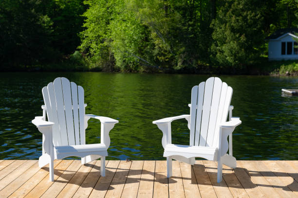 istock Two white Adirondack chairs on a wooden dock 1401452101