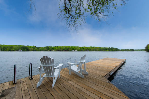 istock Two white Adirondack chairs on a wooden dock 1401452119