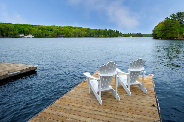 istock Two white Adirondack chairs on a wooden dock 1401452630