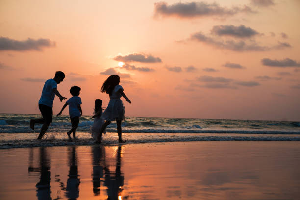 Silhouette family walking and playing at beach sunset with kids happy vacation concept stock photo