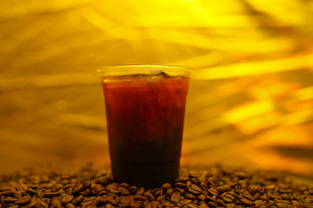 Close Up Iced Black Coffee In Disposable Plastic Cup On Roasted Coffee Bean.