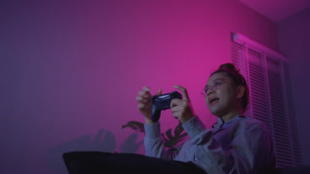 Asian Woman Concentrating on Video Game and Cheering after Beating It.