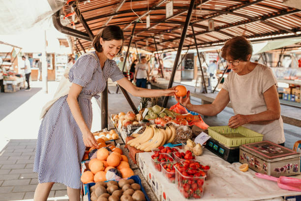 vendedora mujer mayor ofrece verduras frescas y orgánicas en el mercado verde - farmers market fruit market berry fruit fotografías e imágenes de stock