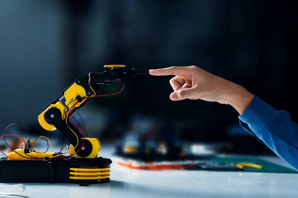 istock Robot arm touches human hand in science classroom. 1401460554