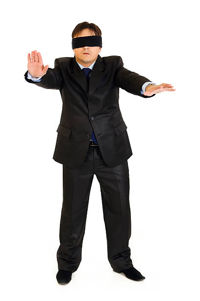 istock Disoriented businessman with blindfold covering his eyes isolated on white. 140146058