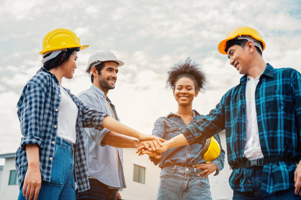 Team of engineer construction workers join hands together on construction site. stock photo