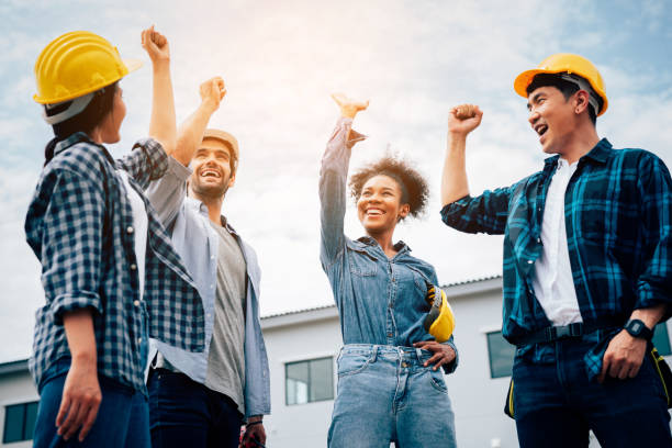 Group of engineers construction and workers raise their hand after achieve their mission. stock photo