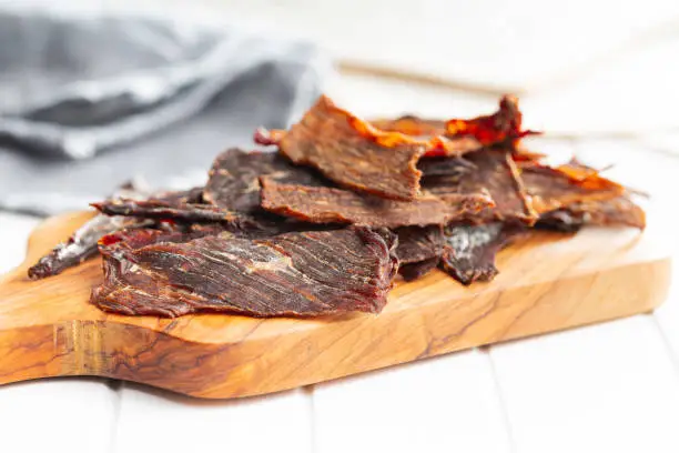 Beef jerky meat. Dried sliced meat on a wooden cutting board.