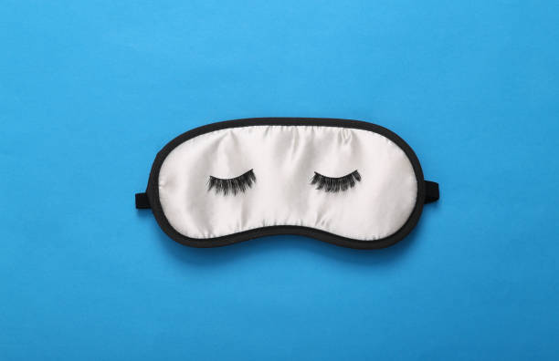istock Sleep mask with closed eyes and eyelashes on blue background. Top view, flat lay. Concept of vivid dreams. Minimal style 1401471884