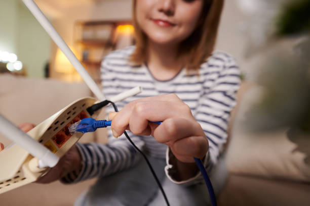 frau steckt ethernet-kabel in modem - modem stock-fotos und bilder