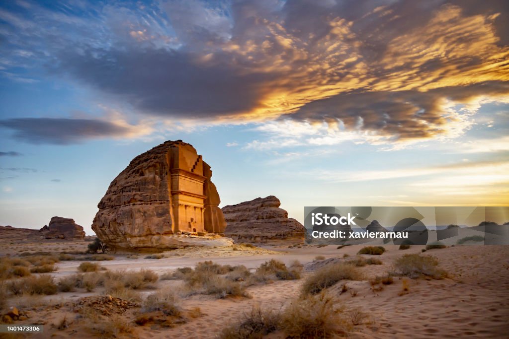 Sunset portrait of tomb of Lihyan, son of Kuza, in Hegra Full view under dramatic sky of iconic tomb also known as Qasr Al Farid, Saudi Arabia’s first UNESCO World Heritage Site erected in 1st-century CE. Saudi Arabia Stock Photo