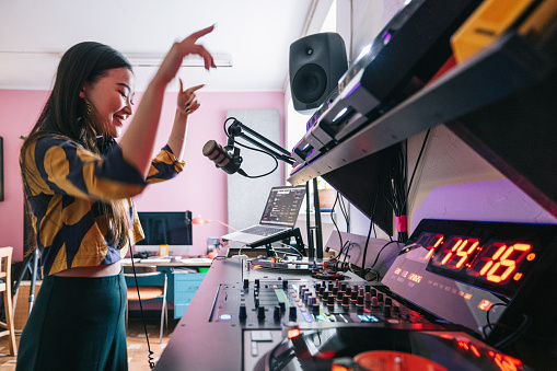 Young Japanse woman making a DJ set in her studio.