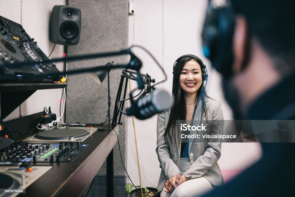 Woman interviewing man in a radio show Japanese Radio host interviewing African-American man. Interview - Event Stock Photo