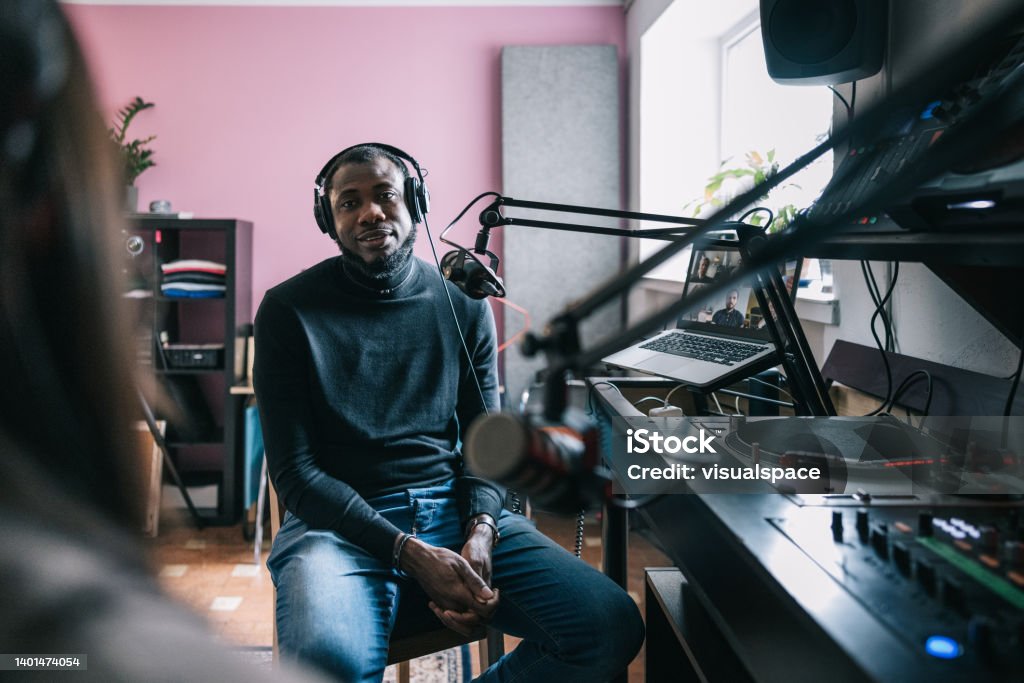 Entrepreneur interviewed on a podcast Candid portrait of African-American entrepreneur interviewed on a radio podcast. Podcasting Stock Photo