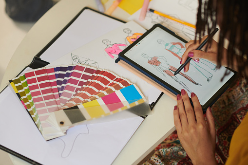 Hands of female designer drawing fashion illustrations on tablet computer