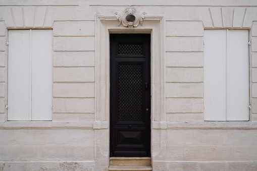 classic black home entrance wooden Door on french wall street facade