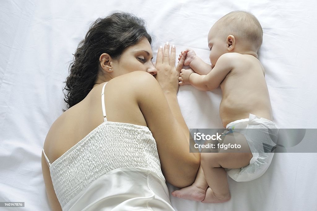 Baby sleeping close to her mother Baby sleeping close to her mother, holding her finger 6-11 Months Stock Photo