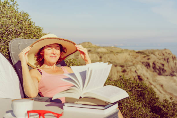 A concentrated Caucasian woman reads a book and lying on the floor.