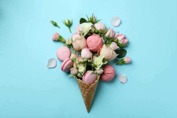 istock Waffle cone with flowers, ice cream balls and macaroons on blue background 1401482677