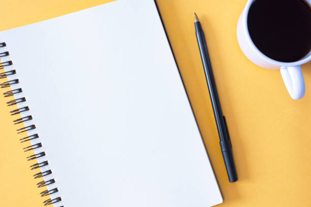 istock Directly above view of notepad, pen and coffee cup on yellow background. 1401483819