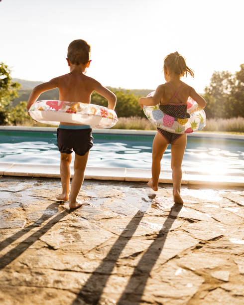 istock Playful siblings going towards the pool in summer day. 1401483912