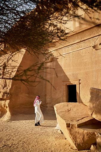 Hombre saudí visitando la cámara funeraria excavada en la roca en Hegra photo